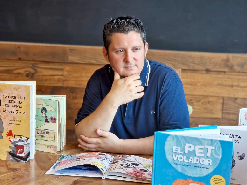 Hombre pensativo rodeado de libros infantiles.